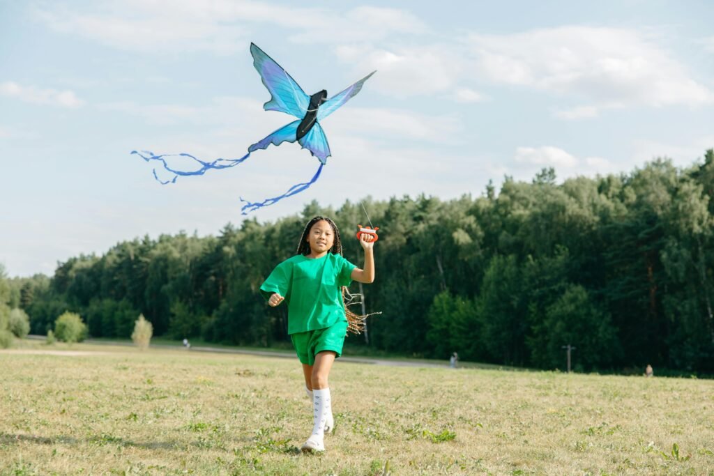 A young girl in vibrant attire enjoys a sunny day flying a kite in a lush green park.